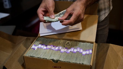 In this June 27, 2017, file photo, the proprietor of a medical marijuana dispensary prepares his monthly tax payment, over $40,000 in cash, at his Los Angeles store.