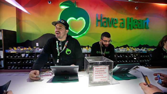 In this March 28, 2019, photo, employees Dan Giroux, left, and Dustin Barrington ring up sales for customers at a marijuana shop in Seattle.