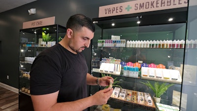 In this March 21, 2019, photo, Gus Dabais looks over CBD products he sells at his Sidewalk Wellness store in San Francisco.