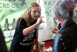 In this April 7, 2019 photo, Lindsey Bouras, left, wellness consultant at The Healthy Place, formerly known as Apple Wellness, talks to an attendee about CBD oil at the, It's Hemp, It's Fine hemp/CBD event, at Monona Terrace Convention Center in Madison, Wisc. The event featured a panel discussion, informational booths, and free samples of CBD coffee, beer, kombucha, candy and more.
