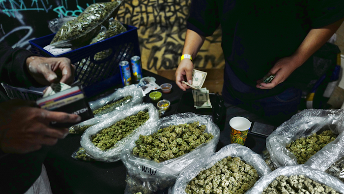 In this April 15, 2019, file photo, a vendor makes change for a marijuana customer at Rev-Up a cannabis marketplace in Los Angeles.