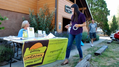 In this June 25, 2015, file photo, Gina Erdmann, director of the Oregon SunGrown Growers' Guild, sets up a sign-in table for the monthly meeting of marijuana growers in the old Williams Grange in Williams, Ore.