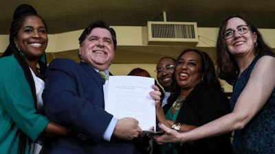Gov. J. B. Pritzker holds a bill that legalizes adult-use cannabis in Illinois, Tuesday, June 25, 2019, in Chicago.