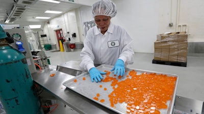 Ioka Tasi works on packaging cannabis-infused mango hard candies at Evergreen Herbal, Wednesday, July 24, 2019, in Seattle.