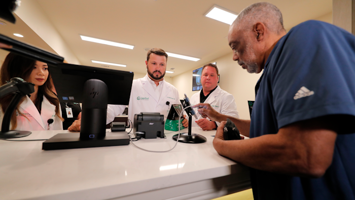 Alex Domino, right, the first ever person to receive medical marijuana in Louisiana, purchases his dose at Capitol Wellness Solutions, in Baton Rouge, La., Tuesday, Aug. 6, 2019.