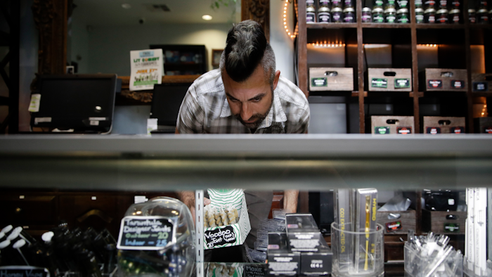 In this June 27, 2017, file photo, Jerred Kiloh, owner of the licensed medical marijuana dispensary Higher Path, stocks shelves with with cannabis products in Los Angeles.
