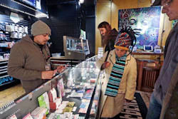In this Jan. 4, 2018, file photo, cannabis consultant Juan Aguilar, left, assists customers in the Herban Legends pot shop in Seattle.