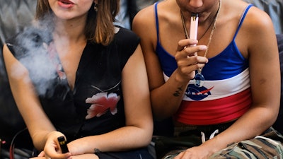 In this Saturday, June 8, 2019 file photo, two women smoke cannabis vape pens at a party in Los Angeles.