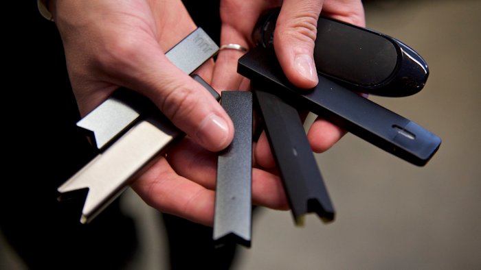 In this April 16, 2019, file photo, a researcher holds vape pens in a lab at Portland State University in Portland, Ore.