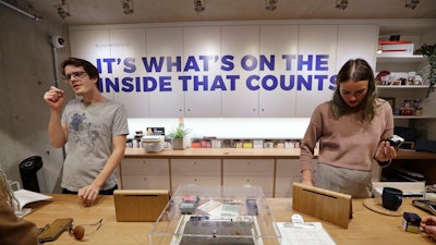 In this Oct. 9, 2019, photo, bloom tenders Rian Bevan, left, and Wallis Hartley assist customers at the Village Bloomery, a marijuana retail shop in Vancouver.