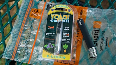 In this May 8, 2019, file photo, a Yolo! brand CBD oil vape cartridge sits alongside a vape pen on a biohazard bag on a table at a park in Ninety Six, S.C.