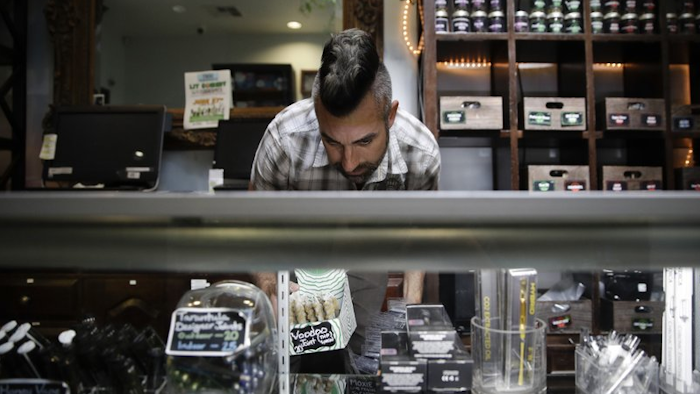 In this June 27, 2017, file photo, Jerred Kiloh, owner of the licensed medical marijuana dispensary Higher Path, stocks shelves with with cannabis products in Los Angeles.
