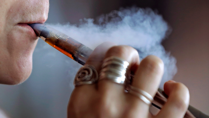 In this Friday, Oct. 4, 2019, file photo, a woman using an electronic cigarette exhales a puff of smoke in Mayfield Heights, Ohio.