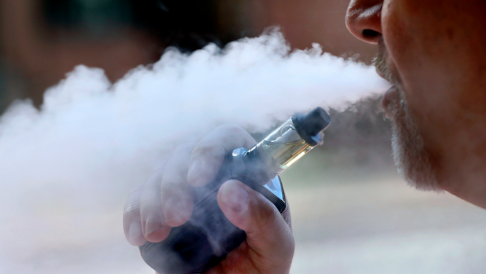 In this Aug. 28, 2019, file photo, a man exhales while smoking an e-cigarette in Portland, Maine.