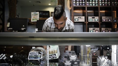 In this June 27, 2017, file photo, Jerred Kiloh, owner of the licensed medical marijuana dispensary Higher Path, stocks shelves with with cannabis products in Los Angeles.