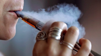 In this Friday, Oct. 4, 2019, file photo, a woman using an electronic cigarette exhales a puff of smoke in Mayfield Heights, Ohio.