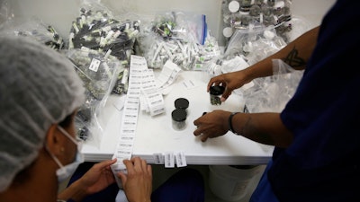 In this June 28, 2017, file photo, workers put barcode stickers on jars of marijuana at the Desert Grown Farms cultivation facility in Las Vegas.