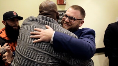 Kevin Hart, of Randolph, Mass., center left, receives a hug from Mike Whittaker, right, director of operations at Pure Oasis, after a meeting of the Massachusetts Cannabis Control Commission, Feb. 6, 2020, in Worcester, Mass.