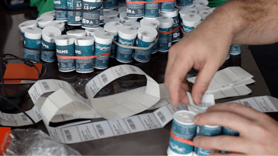 Mike Whittaker, of Quincy, Mass., director of operations at Pure Oasis recreational marijuana shop, applies bar codes to containers of cannabis flowers in the store, Sunday, March 8, 2020, in Boston. Pure Oasis, Boston's first recreational marijuana shop, and the state's first black-owned one, is slated to open, Monday, March 9, 2020.