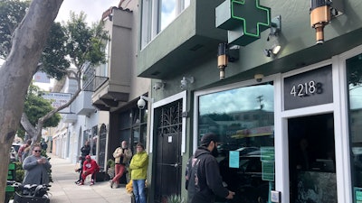 Customers maintain social distance while waiting to enter The Green Cross cannabis dispensary in San Francisco, March 18, 2020.