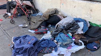 Sleeping people, discarded clothes and used needles on a street in the Tenderloin neighborhood in San Francisco, July 25, 2019.