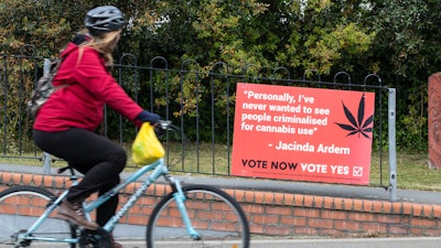 A cyclist rides past a sign in support of making marijuana legal, Christchurch, New Zealand, Oct. 15, 2020.