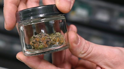 A worker holds up a jar with marijuana offered for sale at Montana Advanced Caregivers, a medical marijuana dispensary, in Billings, Nov. 11, 2020.