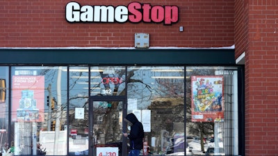 In this Jan. 28, 2021 file photo, a customer checks on his cellphone as he walks to a GameStop store in Vernon Hills, Ill.