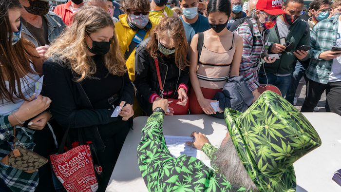 A man wearing a cannabis costume hands out marijuana cigarettes in New York during a 'Joints for Jabs' event, April 20, 2021.