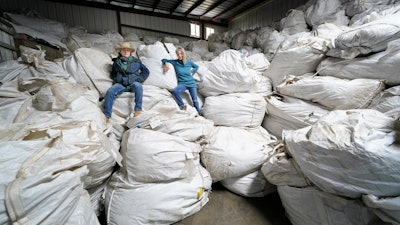 Gail Hepworth, right, and Amy Hepworth, sisters and co-owners of Hepworth Farms, pose on bags full of hemp plants at Hepworth Farms in Milton, N.Y., April 12, 2021.