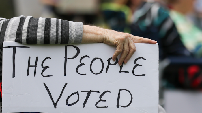 A rally attendee props up a sign with her hand while listening to speakers at the Missouri State Capitol in Jefferson City, April 27, 2021.