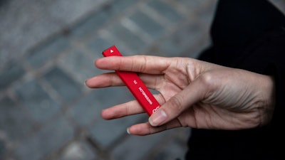 A woman holds a Puff Bar flavored disposable vape device in New York, Jan. 31, 2020.