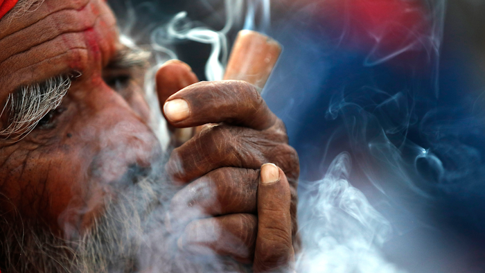 A Hindu holy man smokes marijuana in the courtyard of Pashupatinath temple during Shivratri festival, Kathmandu, Nepal, March 11, 2021.