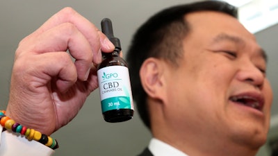 Thailand Public Health Minister Anutin Chanvirakul shows a bottle of extracted cannabis oil during a press conference in Bangkok, Aug. 7, 2019.
