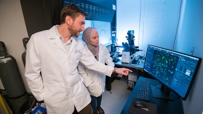 Jason Paris (left) and fourth-year graduate student Alaa Qrareya image calcium in cultured neural cells in Paris’ laboratory in 2019 at the School of Pharmacy, Oxford, Miss.