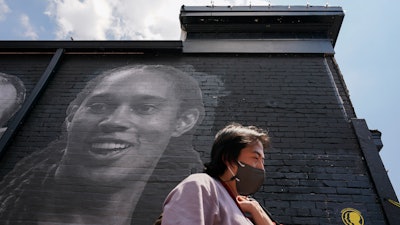 A visitor walks down an alley past a mural depicting WNBA star Brittney Griner, top left, and other American hostages and wrongful detainees who are being held abroad, Wednesday, July 20, 2022, in the Georgetown neighborhood of Washington.