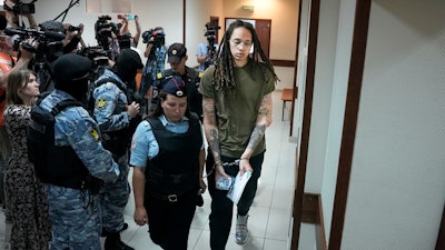 WNBA star and two-time Olympic gold medalist Brittney Griner is escorted in a court room prior to a hearing, in Khimki just outside Moscow, Russia, Tuesday, Aug. 2, 2022. Since Brittney Griner last appeared in her trial for cannabis possession, the question of her fate expanded from a tiny and cramped courtroom on Moscow's outskirts to the highest level of Russia-US diplomacy.