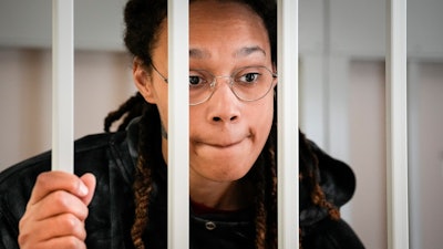 WNBA star and two-time Olympic gold medalist Brittney Griner speaks to her lawyers standing in a cage at a court room prior to a hearing, in Khimki just outside Moscow, Russia, Tuesday, July 26, 2022.
