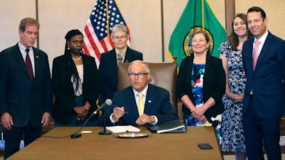 Gov. Jay Inslee signs Senate Bill 5536 concerning controlled substances on Tuesday, May 16, 2023, in Olympia, Wash. Behind him are from left to right: Rep. Roger Goodman, D- Kirkland, Rep. Jamila Taylor, D-Federal Way, House Speaker Laurie Jinkins, D-Tacoma, June Robinson, D-Everett, an identified woman and Andy Billig, D-Spokane.