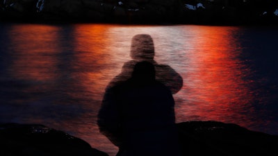 In this photo made with a long exposure, a man is silhouetted against lights reflected in the waters off Cape Neddick in Maine on Dec. 11, 2017. A study published Thursday, Sept. 14, 2023, in the journal Nature Medicine has found that the psychedelic drug MDMA, combined with talk therapy, can reduce symptoms of post-traumatic stress disorder.