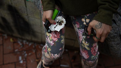 A person holds drug paraphernalia near the Washington Center building on SW Washington St. in downtown Portland, Ore., where heavy drug use has become common.