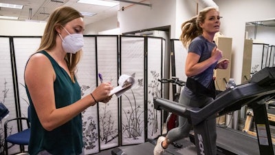 Boulder-based ultrarunner Heather Mashhoodi runs on the treadmill in 2021 as part of a study exploring how cannabis influences exercise. First author Laurel Gibson, left, takes notes. Study participants used cannabis on their own at home before being picked up and driven to the lab for testing.