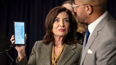 New York Gov. Kathy Hochul holds up a phone that displays a map of illegal cannabis stores as entrepreneur Alfredo Angueira looks on during a press conference, Wednesday, Feb. 28, 2024 in New York. Unable to reign in illegal cannabis shops in New York, the state's governor is asking digital mapping and search companies to hide or relabel the many illegal shops.