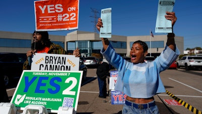 Nikko Griffin, left, and Tyra Patterson, call out to arriving voters for several issues, including Issue 2, legalizing recreational marijuana, at a parking lot during early in-person voting in Cincinnati, Nov. 2, 2023.