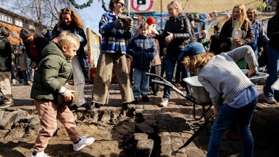 Citizens of the free village Christiania jointly dig up the cobblestones at Pusher Street, in Copenhagen, Denmark, Saturday April 6, 2024. After the cobblestones are removed, new water pipes and a new pavement will be laid on Pusher Street and nearby buildings will be renovated. That is the first step in an overall plan to turn the hippie oasis into an integrated part of the Danish capital area, although “the free state' spirit of creativity and community life is to be maintained.