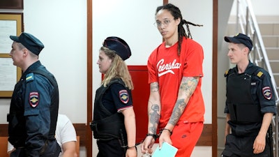 WNBA star and two-time Olympic gold medalist Brittney Griner, second from right, is escorted to a courtroom for a hearing in Khimki outside Moscow, Russia, July 7, 2022. Griner continues her efforts to settle into a normal routine following her release from a Russian prison 17 months ago.