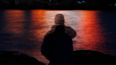 In this photo made with a long exposure, a man is silhouetted against lights reflected in the waters off Cape Neddick in Maine on Dec. 11, 2017. Federal health advisers are considering the first request to approve the mind-altering club drug MDMA as a treatment for PTSD. The advisers to the Food and Drug Administration are scheduled to vote on the drug's safety and effectiveness Tuesday, June 4, 2024, potentially setting the stage for federal approval later this year.