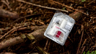 A container of Narcan, or naloxone, sits on tree roots at a longstanding homeless encampment in Bellingham, Wash., on Thursday, Feb. 8, 2024.