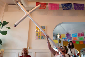 Drag performer Ed Du'Bull holds a cross made to look like lit joints and pretends smoke from it while performing during a 'blaze and praise' drag brunch at Bar Carlo on Sunday, April 20, 2025, in Portland, Ore.