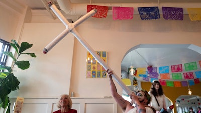 Drag performer Ed Du'Bull holds a cross made to look like lit joints and pretends smoke from it while performing during a 'blaze and praise' drag brunch at Bar Carlo on Sunday, April 20, 2025, in Portland, Ore.